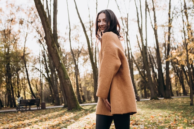 写真 暖かい日当たりの良い秋の公園で若い女性の屋外ポートレートを歩く魅力的なきれいな女性