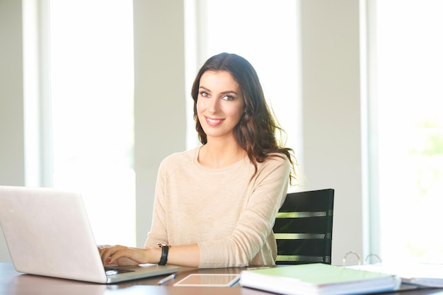 Attractive professional business woman working with laptop and digital tablet at office