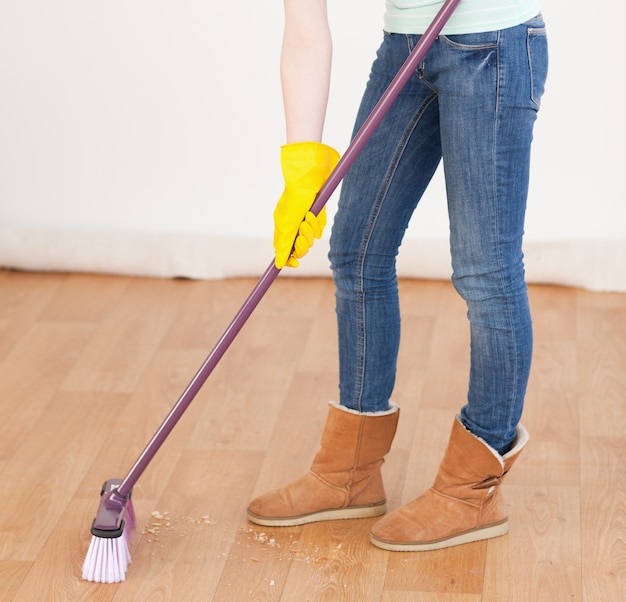 Photo attractive red-haired woman sweeping the floor at home