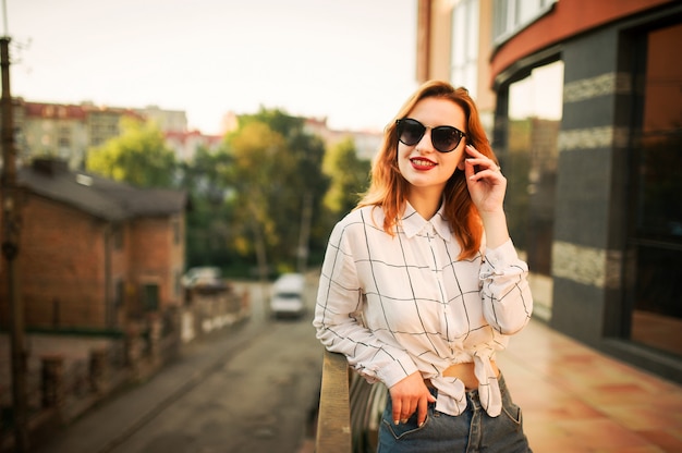 Attractive redhaired woman in eyeglasses wearing on white blouse 