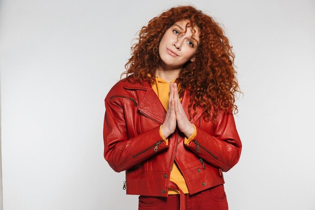 an attractive redhead young woman standing isolated, hands sealed