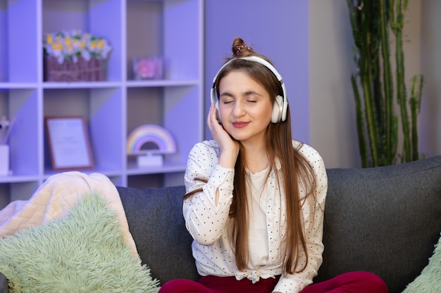 Attractive schoolgirl listening music through headphones, eyes closed