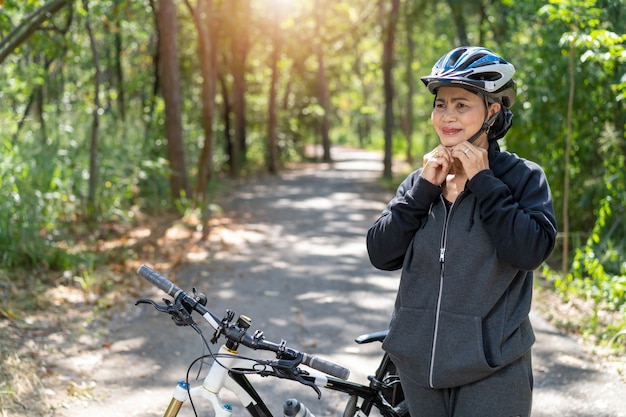 Привлекательная старшая азиатская женщина с велосипедом в парке