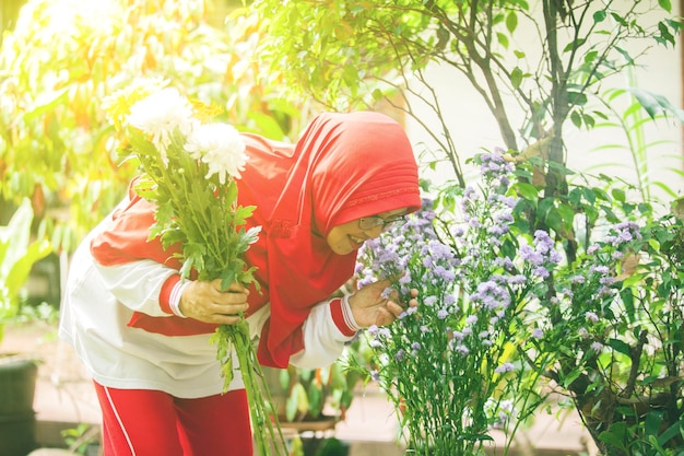 花にキスをする魅力的な年配のイスラム教徒の女性