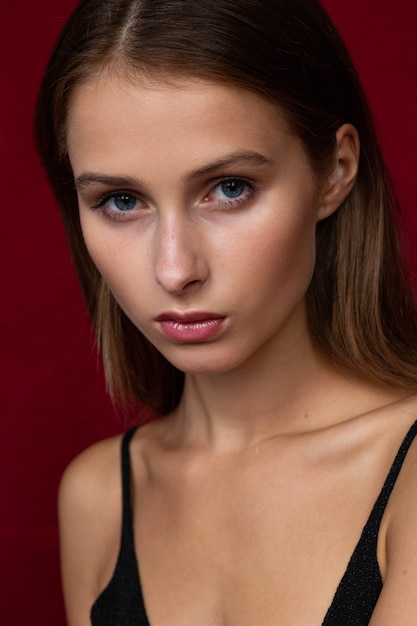 Attractive and serious brunette woman's close-up portrait on dark-red background