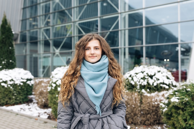 Attractive serious Face young woman looking at camera beautiful curly hair stand on street city lifestyle winter girl city outdoors.