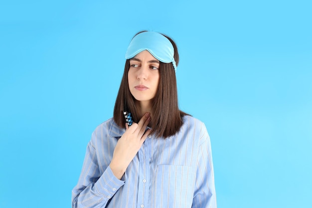 Attractive sick woman in sleep mask on blue background