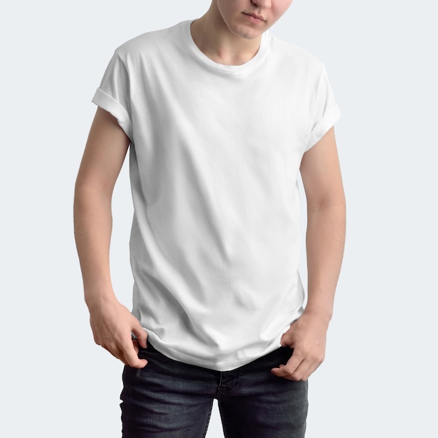 Attractive slim guy in a blank T-shirt and dark jeans on a white studio background. Frontal pose. 
Mockup can be used in your showcase.