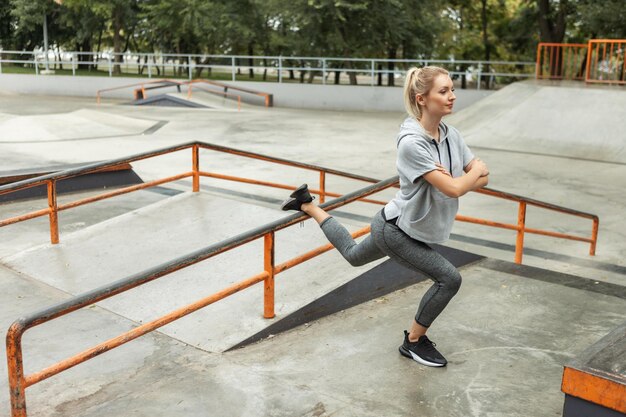 Attractive slim woman practicing lunge on skate ground. Outdoor sports