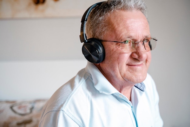 Attractive smiling grandfather listening to music enjoying himself Technology concept