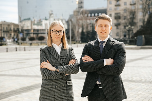 Attractive smiling happy couple of businessmen in formal office suits in the city