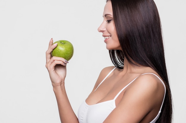 Привлекательный портрет улыбающейся женщины на белом фоне с яблоком