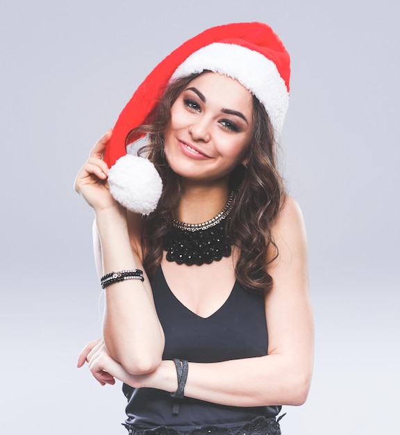 회색 배경 위에 절연 산타 모자에 매력적인 웃는 여자