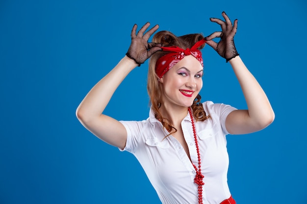 An attractive smiling woman in an unbuttoned shirt adjusts her headband, pin-up style