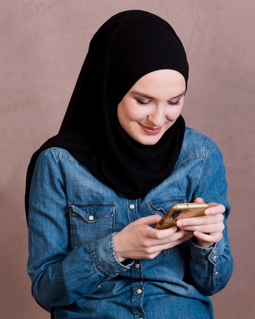 Foto donna sorridente attraente che per mezzo del telefono cellulare sopra il contesto