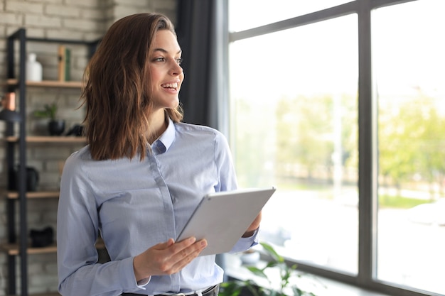 Attractive smiling woman working on a tablet in a home office.