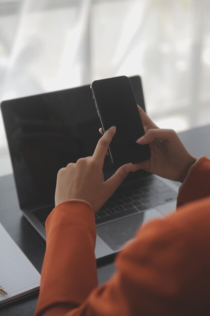 Attractive smiling young asian business woman work at home office Asian woman working on laptop computer holding tablet