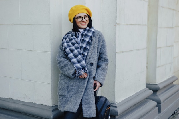Attractive smiling young woman in glasses in coat and yellow beret