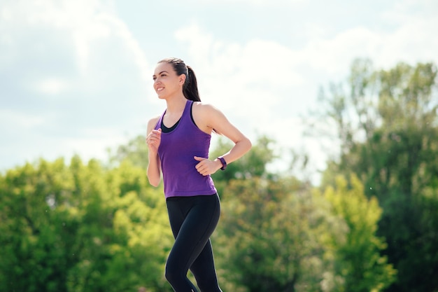 Attractive sporty woman running in park Happy face Sunny day for sport