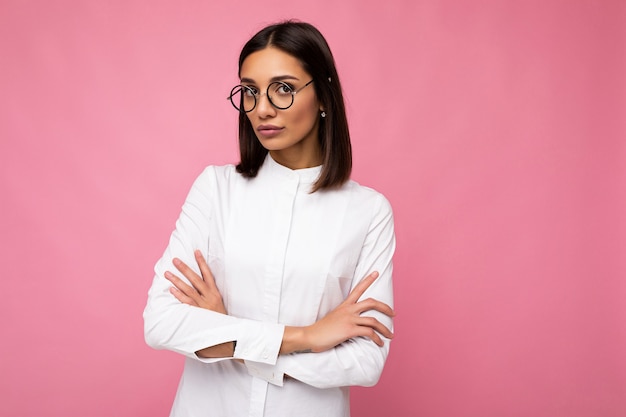 Attractive strict serious young brunette businesswoman wearing everyday stylish clothes and modern optical glasses isolated on colorful background wall looking at camera. copy space