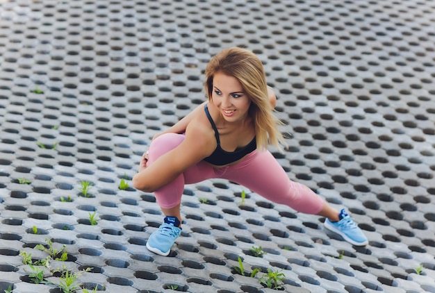 Attractive and strong woman stretching before fitness in the summer park Sports concept Healthy lifestyle