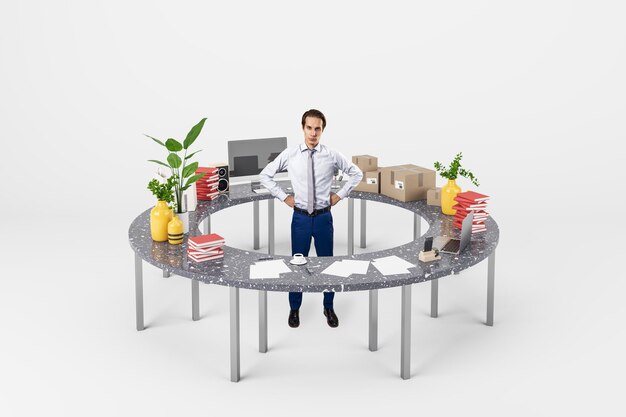 Attractive thoughtful young businessman standing inside round table with many items on white background Hobby and occupation choice concept