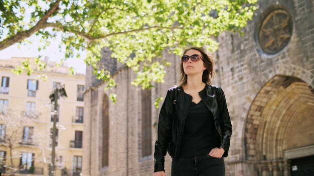 Attractive tourist woman in sunglass with backpack walking through street