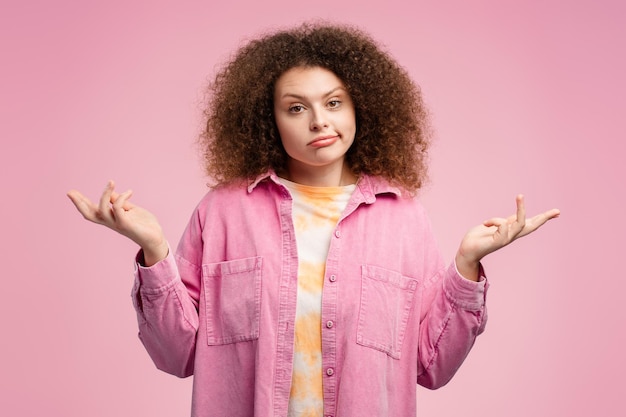 Foto attraente, sconvolta, dai capelli ricci, giovane donna che indossa abiti casuali non sa cosa scegliere.