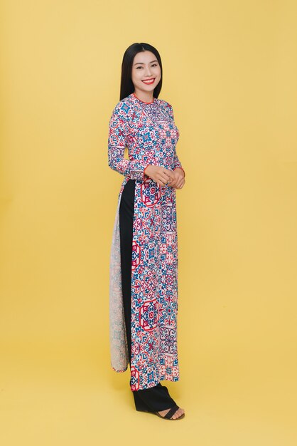 Attractive Vietnamese woman wearing traditional costume, isolated on yellow background