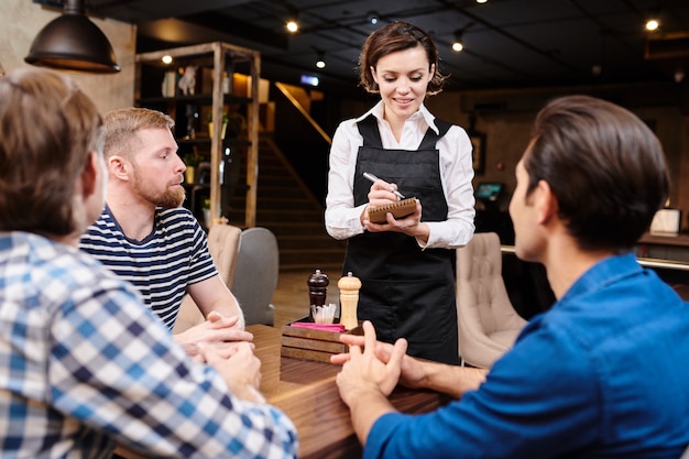 Attractive waitress talking to friends in loft restaurant