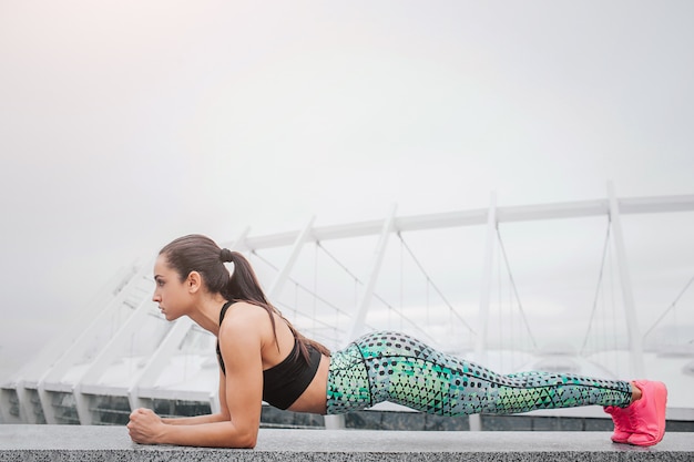 Attractive and well-built young woman stands in plank position