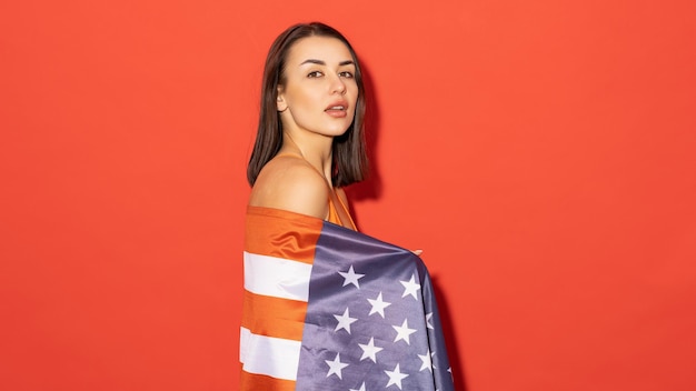 赤い背景にアメリカ国旗を持つオレンジ色の水着を着た魅力的な白人女性 レクリエーションと愛国心の概念 アメリカの夏休み