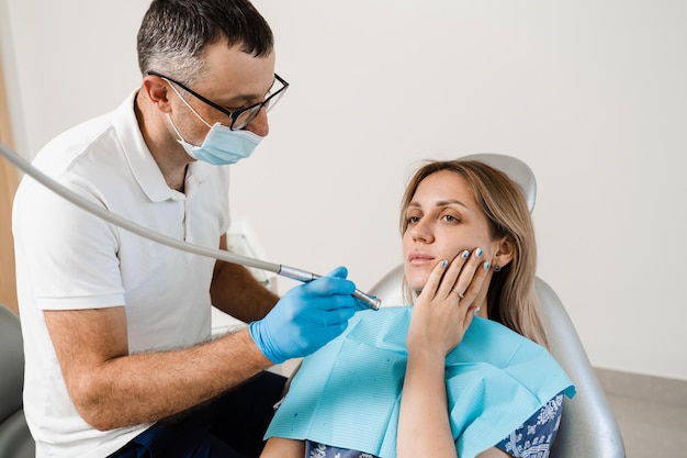 Attractive woman afraid of dentist Dentist consults frightened girl in dentistry Treatment of teeth and toothache in dentistry