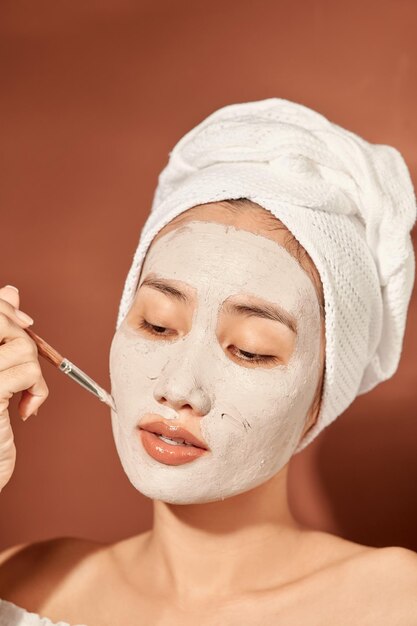 Attractive woman applying clay mask on her face