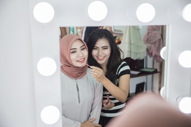 Attractive woman applying make up to her friend
