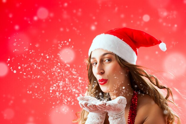 Photo attractive woman as santa claus blowing snow