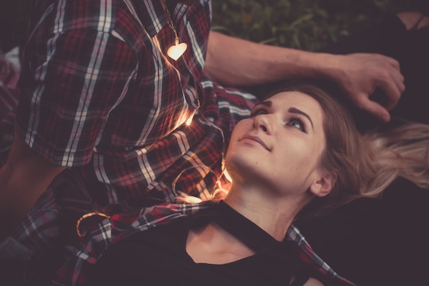 Attractive woman and beard man looking each other faces lit by the light of garland Dating outdoor