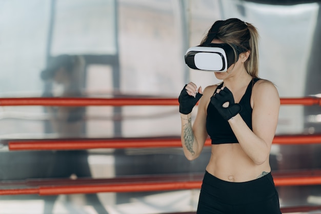 Attractive woman boxing in VR 360 headset training for kicking in virtual reality