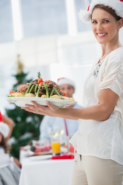 クリスマスディナーでローストチキンを持っている魅力的な女性