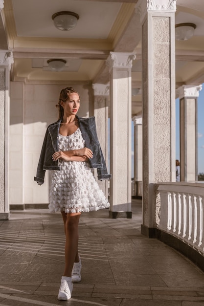 An attractive woman celebrates life in a summer white dress and denim jacket