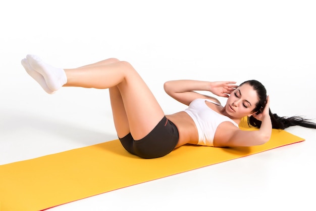 Attractive woman doing exercises brunette fit body on yoga mat