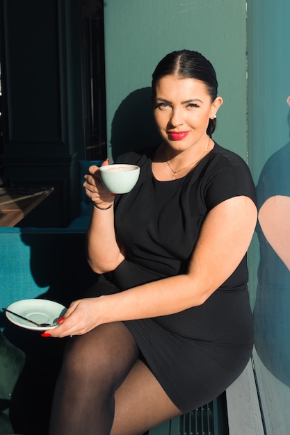 Attractive woman drink coffee in cafe sunny day light and shadows