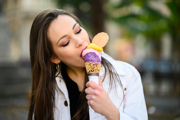 Attractive woman eating ice cream on the city street