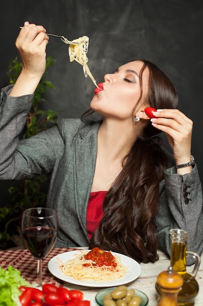 Foto donna attraente che mangia pasta italiana piccante in un ristorante