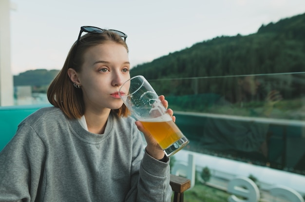 Привлекательная женщина, наслаждаясь бокалом пива на лесном и озерном ландшафте