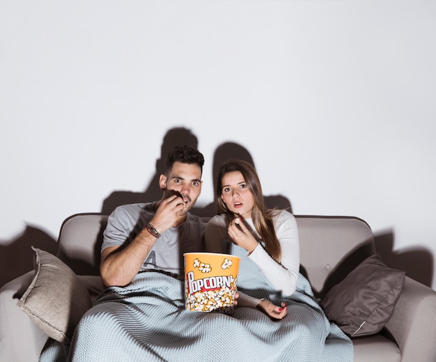 Foto donna attraente e uomo bello guardare la tv e mangiare popcorn sul divano