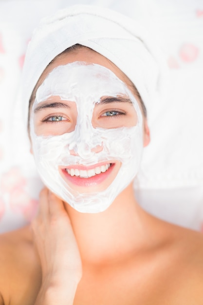 Attractive woman having white cream on her face at spa center