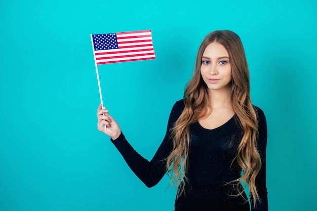 Attractive woman holding an American flag in her hand on a blue background in the studio concept of Independence Day of Independence of America July 4