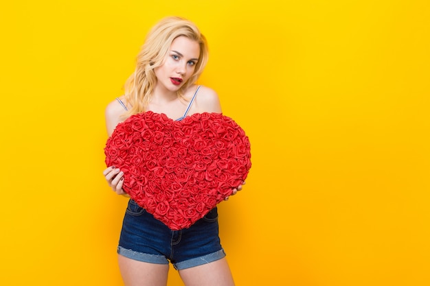 Attractive woman holding big red flower heart