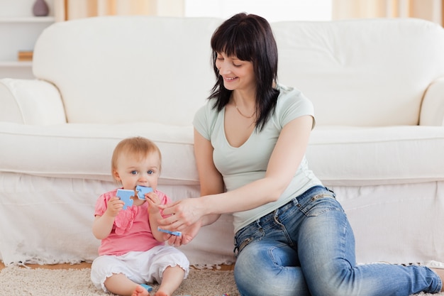 Attractive woman holding her baby in her arms while sitting on a carpet